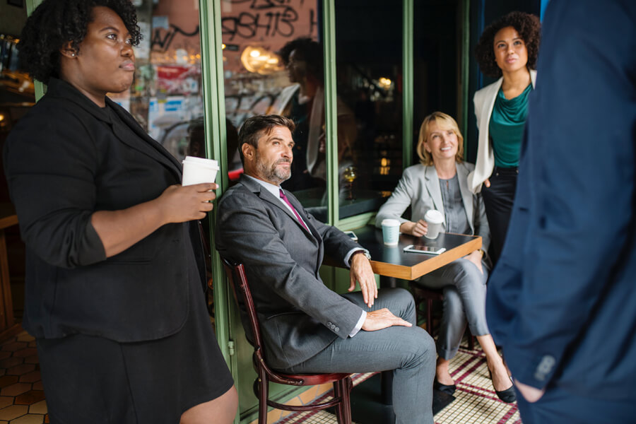 A group of business people casually discussing at an outdoor bistro.