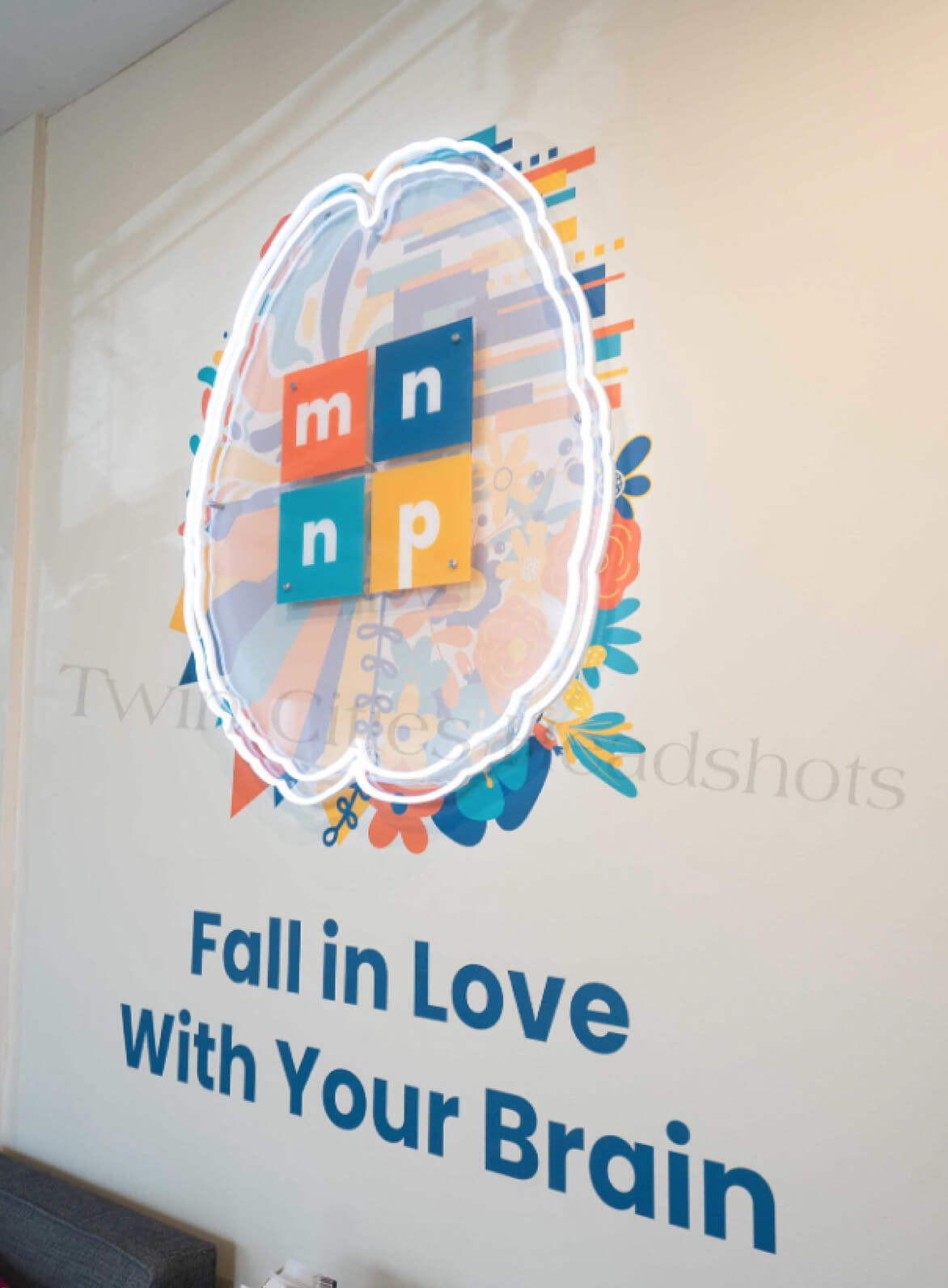 Wall mural displaying Minnesota Neuropsychology logo with colorful brain illustration and text reading 'Fall in Love With Your Brain.'
